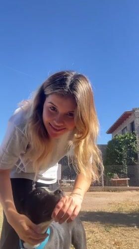 Woman pets dog, takes selfie in sunny Sumalao yard