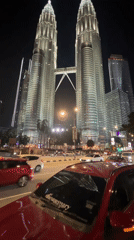 Night traffic flows past illuminated Petronas Towers in Kuala Lumpur