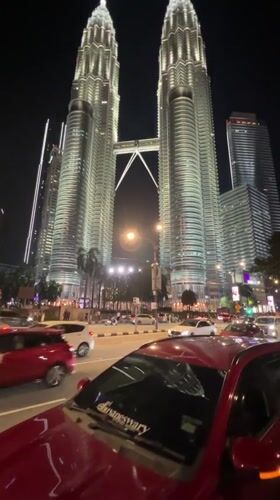 Night traffic flows past illuminated Petronas Towers in Kuala Lumpur
