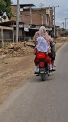 Woman and child ride electric scooter in Indonesian residential area