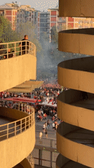 Large crowd gathers on Milan street, observed from parking structure