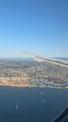 Coastal city sprawls below as a plane passes overhead
