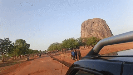 Vehicle travels damaged dirt roads amid sparse landscape