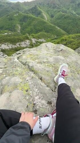 Hiker rests on rocky summit overlooking Bulgarian mountain forests