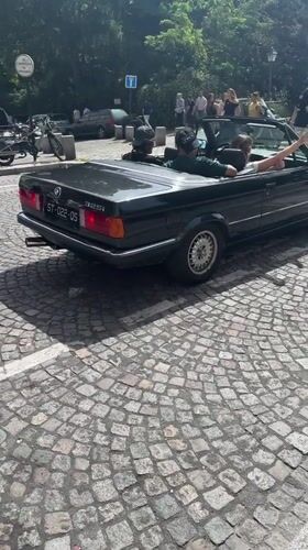 Group gathers with BMW convertible on Paris cobblestone street