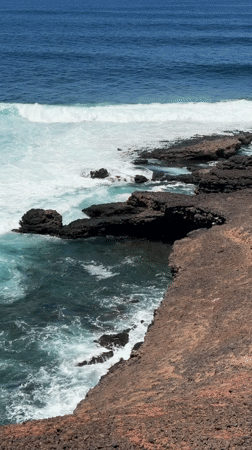 Waves crash against rocky coastline near Tinajo, Spain