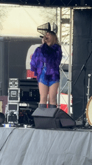 Woman performs in sequined outfit on outdoor stage in Norwich
