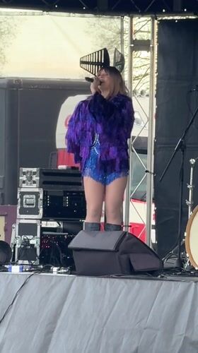 Woman performs in sequined outfit on outdoor stage in Norwich
