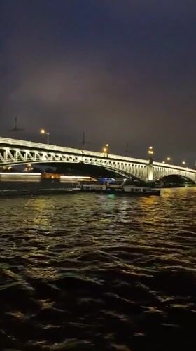 Night cruise past an illuminated bridge in St. Petersburg