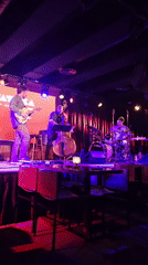 Three-piece band performs on illuminated stage
