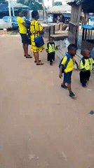 Women with uniformed children gathered in dusty Onitsha street