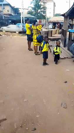 Women with uniformed children gathered in dusty Onitsha street