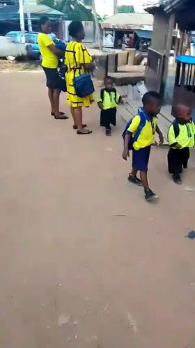 Women with uniformed children gathered in dusty Onitsha street