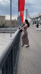 Woman in brown dress pauses on Moscow bridge