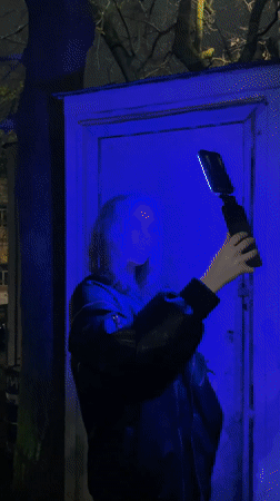 Person tests color-changing light device in nighttime Moscow