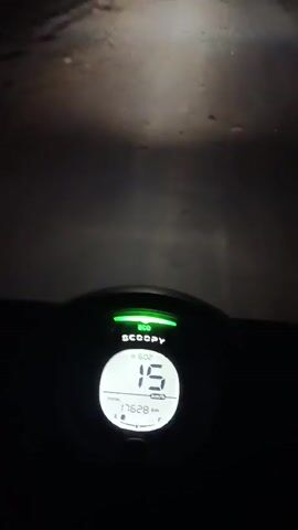 The video shows a first-person perspective of someone riding a bicycle at night. The bicycle's headlight illuminates the path ahead, revealing a dark, paved surface that appears to be a road or trail. The digital display of the bicycle's computer is visible in the lower center of the frame, showing a speed of 14 and a distance of 1762.0 km. The display also indicates that the bicycle is in motion. The overall environment is dark, suggesting that it is nighttime. There are no other people or vehicles visible in the frame.