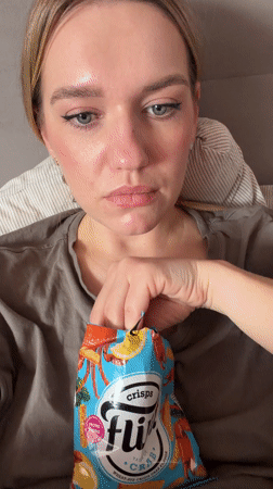 Woman enjoys crab crisps, relaxes in Dreiliņi apartment
