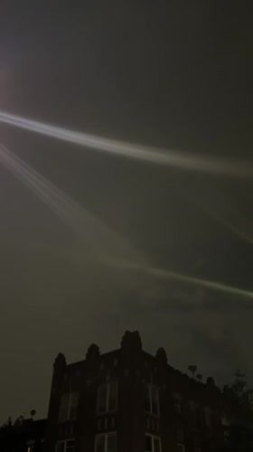 Light beams streak across New York sky above brick buildings