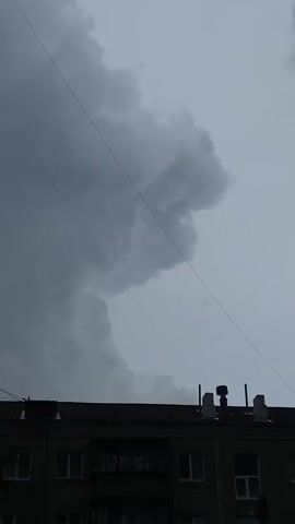 The video shows a time-lapse of storm clouds forming and moving across the sky above a dark, silhouetted building. The clouds are dark and ominous, suggesting an approaching storm. The building appears to be an apartment building or similar structure, with windows and a rooftop. There are power lines visible in the foreground, adding to the urban setting. The overall mood of the video is somber and dramatic, emphasizing the power and unpredictability of nature.