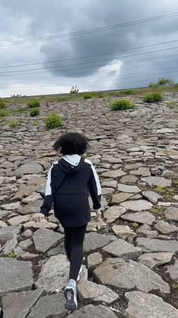 Runner climbs rocky slope in Kryvyi Rih under cloudy skies