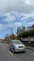 Busy midday traffic on a sunny Klungkung street