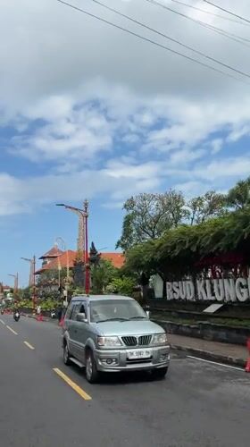 Busy midday traffic on a sunny Klungkung street