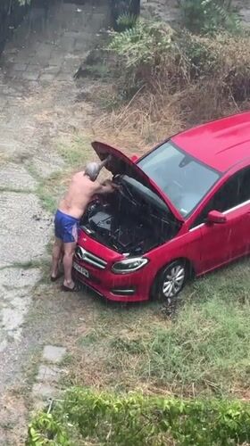 Engine work on a red Mercedes during a Burgas rainstorm