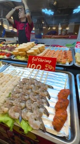 Street food vendor serves grilled skewers at Pattaya night market