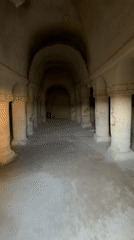 Stone corridor with arched ceiling and pillars documented