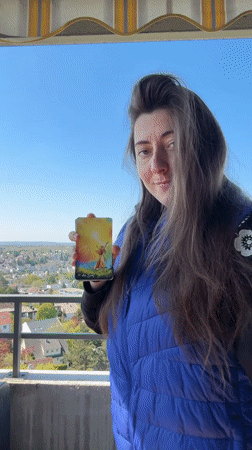 Woman displays tarot card from balcony in Waiblingen