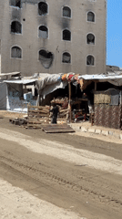 Makeshift market stalls operate in front of war-damaged buildings in Gaza