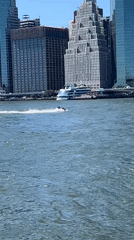 Jet ski and Brooklyn Ferry share the waterway near NYC skyline