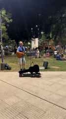 Street musician performs guitar in Córdoba park at night