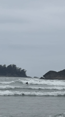 Surfer paddles through choppy waters near Tofino on overcast evening