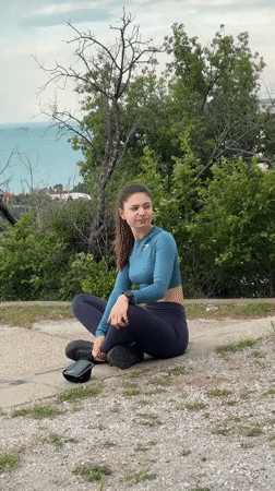 Woman interacts with gray cat near Varna concrete wall