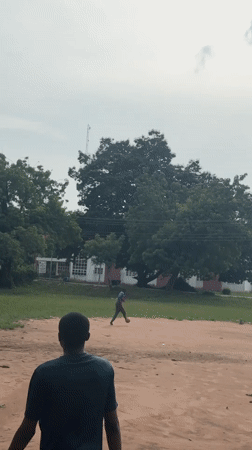 Two play football on dirt field in Ihiagwa, Nigeria