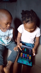 Kids share a tablet, playing a colorful matching game together.