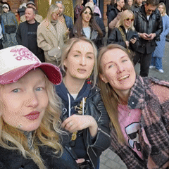 People gather behind railings at brick building, some with eggs