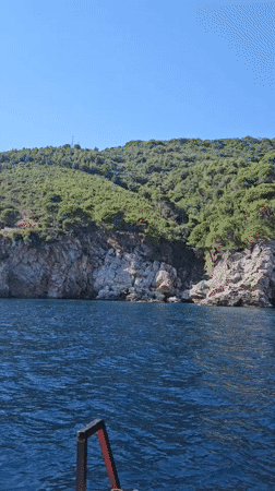 Boat cruising the rugged Montenegrin coastline on a summer afternoon
