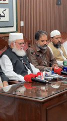 Panel or press conference setting with microphones and seated speakers