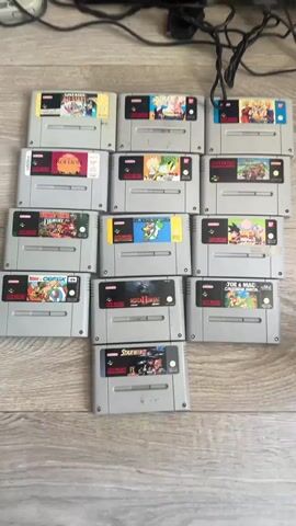The video shows a collection of Super Nintendo games, controllers, and consoles spread out on a light-colored wooden floor.  The camera pans up to show a television screen displaying the title screen of "Street Fighter II Hyper Fighting." The setup suggests a retro gaming session.