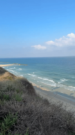 Surfers and boats along Netanya's coast on a calm morning