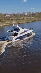 Yacht and barge traffic observed on river during sunny afternoon