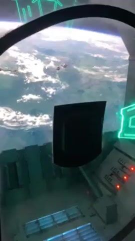 The video shows a view from what appears to be a spaceship cockpit. Through the window, the earth is visible with clouds and blue oceans. Several spacecraft, resembling X-wings from Star Wars, are seen flying in front of the planet. The cockpit has several control panels and buttons, some of which are lit with green neon lights and red LEDs. A speaker's voice can be heard.