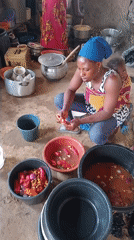 Woman prepares red peppers in kitchen with family present