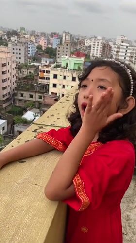 Rooftop dancing in traditional dress above Dhaka's dense skyline