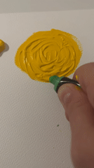 Artist paints yellow flower with green stem on canvas