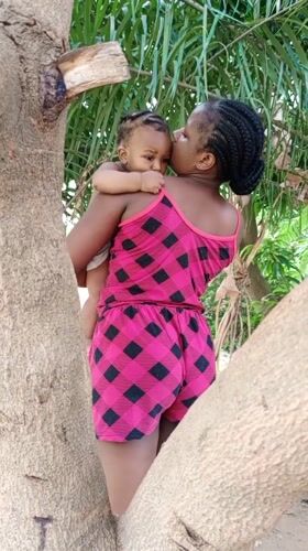 Woman plays with baby in outdoor yard in Keffi