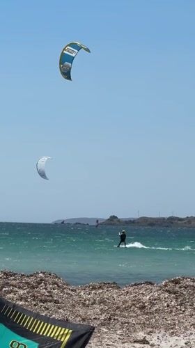 Kitesurfers launch and ride off a seaweed-lined Lemnos beach