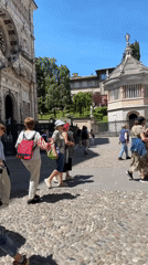 Tourists explore historic Bergamo square on sunny morning